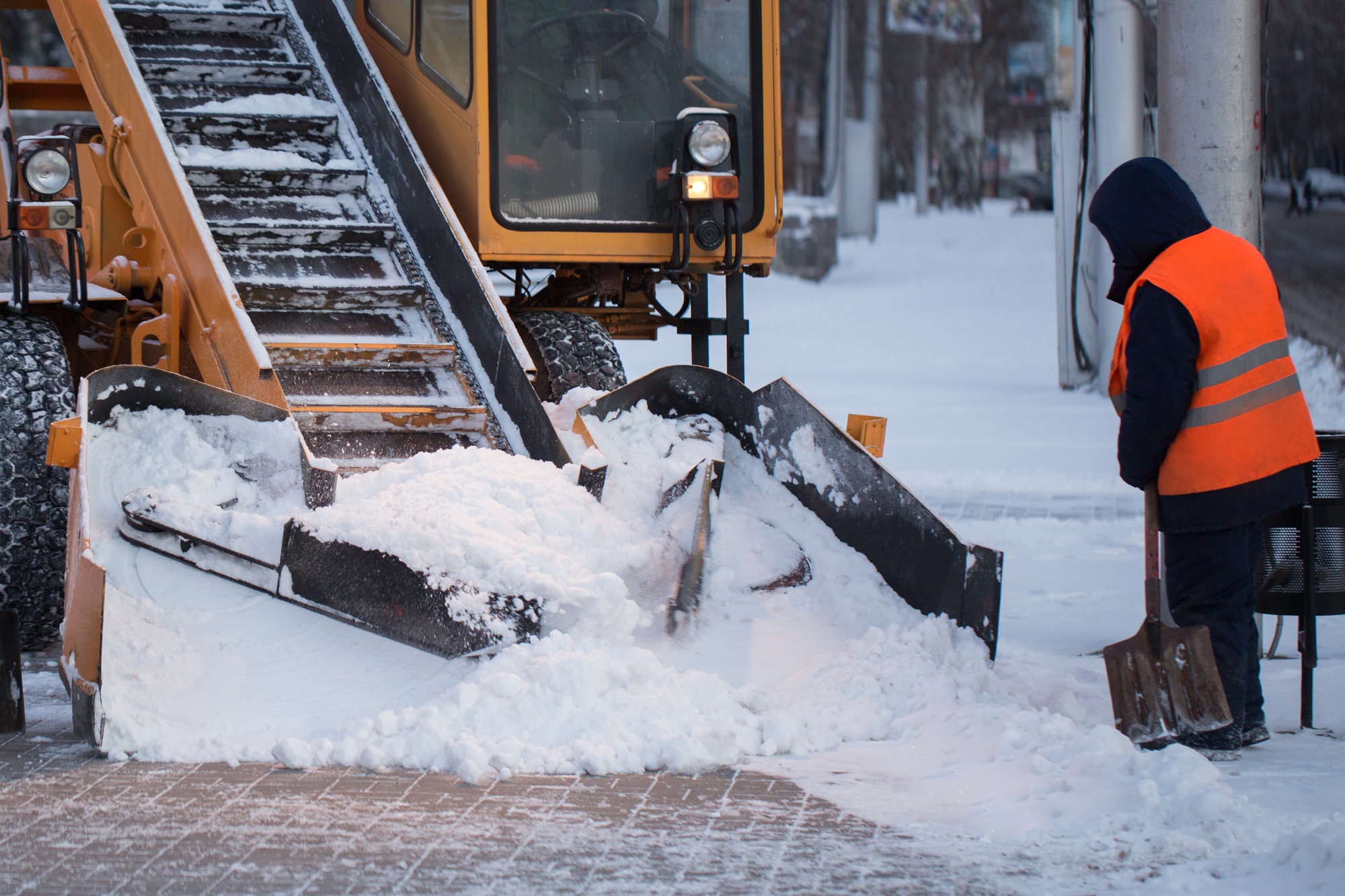 Tractor cleaning the road from the snow. Excavator cleans the streets of large amounts of snow in