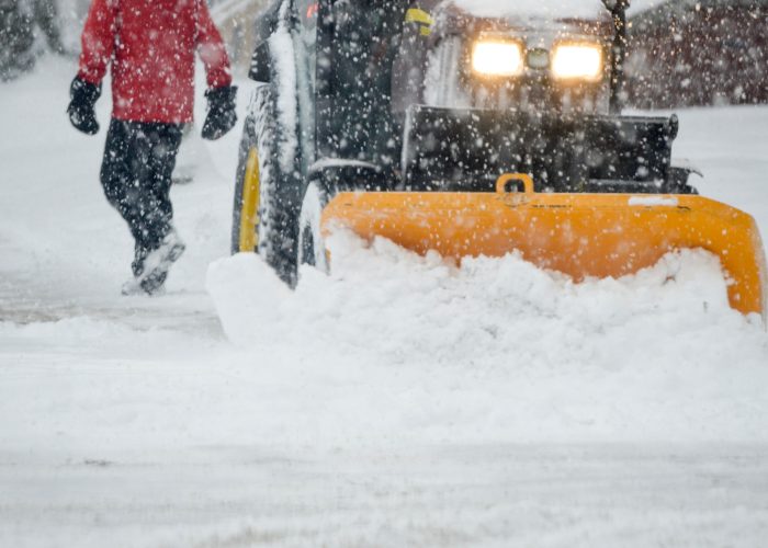 A person walking in a Snowstorm with a snow plow clearing street in heavy snow fall urban winter