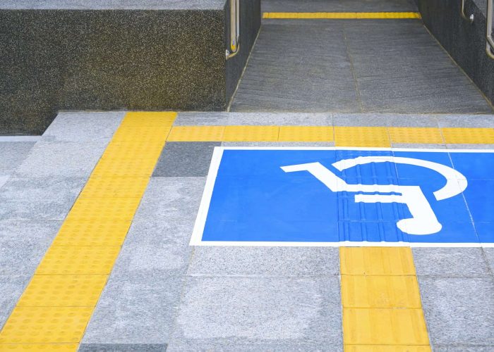 Disabled wheelchair sign with ramp and yellow tactile paving line on different level marble pavement